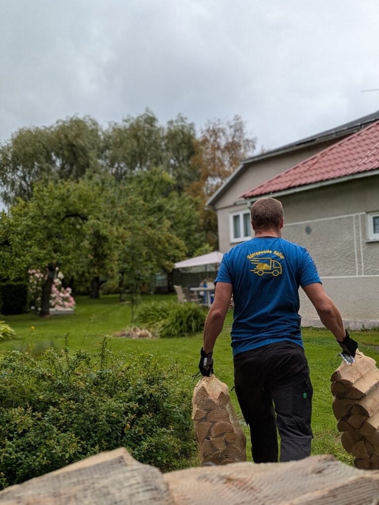 Küttepuude Kulleri töötaja kannab kuivad küttepuud Tartu kodu õue